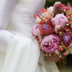 Bride in white dress holding bouquet of colourful flowers