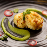 fish cakes on a black plate with green garnish