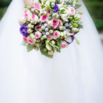 Bride in white dress holds a colourful bouquet