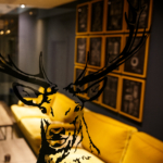 Close up of a stag print on glass in the foreground with the bar area with yellow sofas blurred in the background
