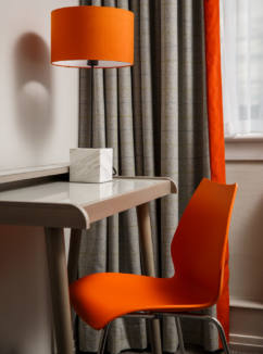Close up of desk, orange chair and lamp in privilege room at mercure inverness hotel