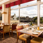 Dining tables and chairs next to a window overlooking the River Ness in the restaurant at mercure inverness hotel